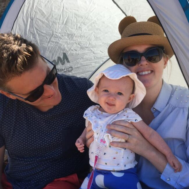 Parents in shade on beach with baby